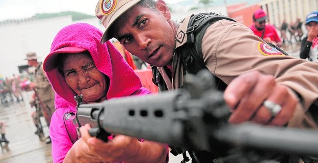 Un miembro de la milicia enseña a una mujer usar un rifle. :: reuters