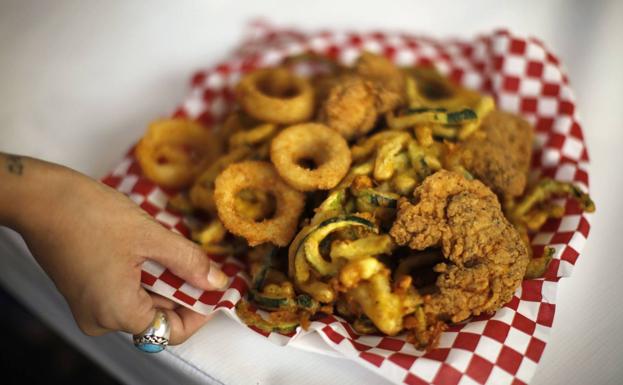 Una mujer sostiene un plato de comida frita./Lucy Nicholson