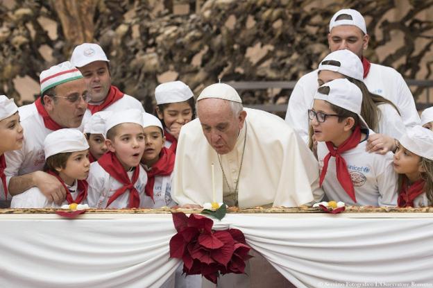 El Papa sopla, ayer, junto a un grupo de niños, la vela que preside una pizza de cuatro metros. :: AFP/