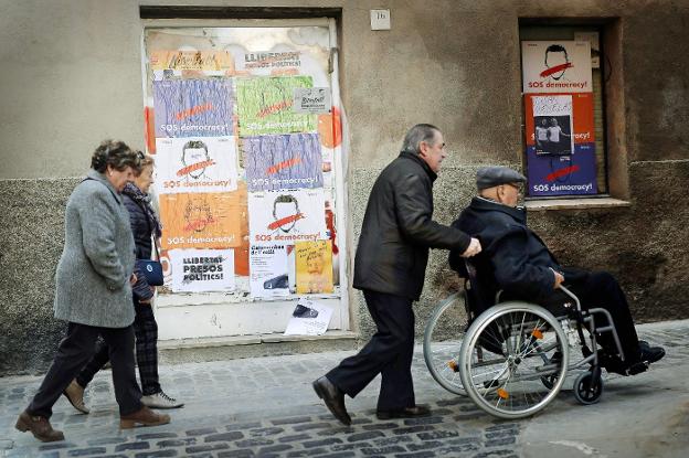 Un grupo de vecinos pasa frente a varios carteles independentistas en una calle de Vic. :: pau barrena/afp/