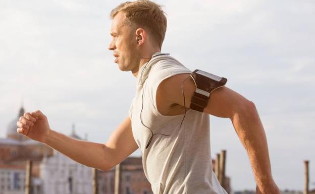 Un hombre corre con un smartphone en el brazo.