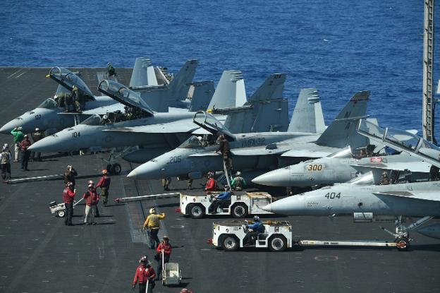 Los marinos revisan los cazabombarderos F-18 en la cubierta de vuelo del portaaviones 'Theodore Roosevelt'. :: TED ALJIBE / afp/