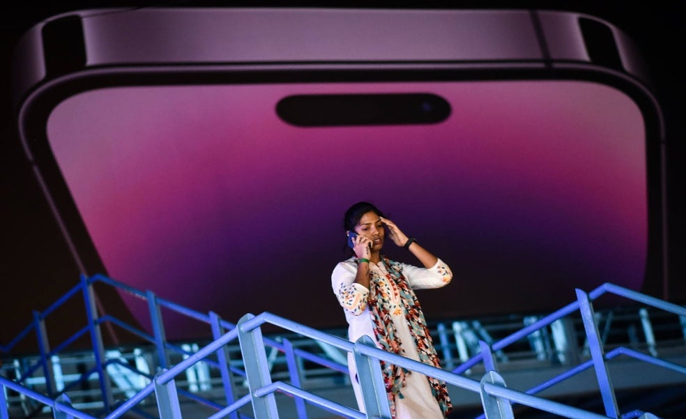 Una mujer habla frente a una publicidad del último iPhone 14./efe