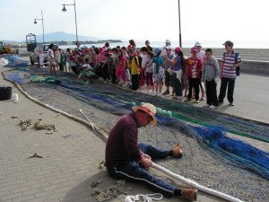 Un grupo de escolares observa cómo trabaja un pescador con las redes. ::
S. V./