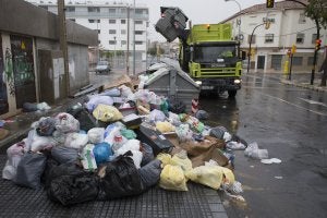 Un camión de Limasa retira la basura de los contenedores, que están prácticamente cubiertos por bolsas de residuos. :: ÑITO SALAS/