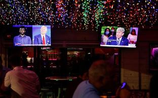 Varios ciudadanos siguen las interrvenciones de Trump y Biden./Reuters