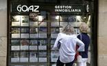 Dos mujeres miran anuncios en el escaparate de una inmobiliaria/archivo